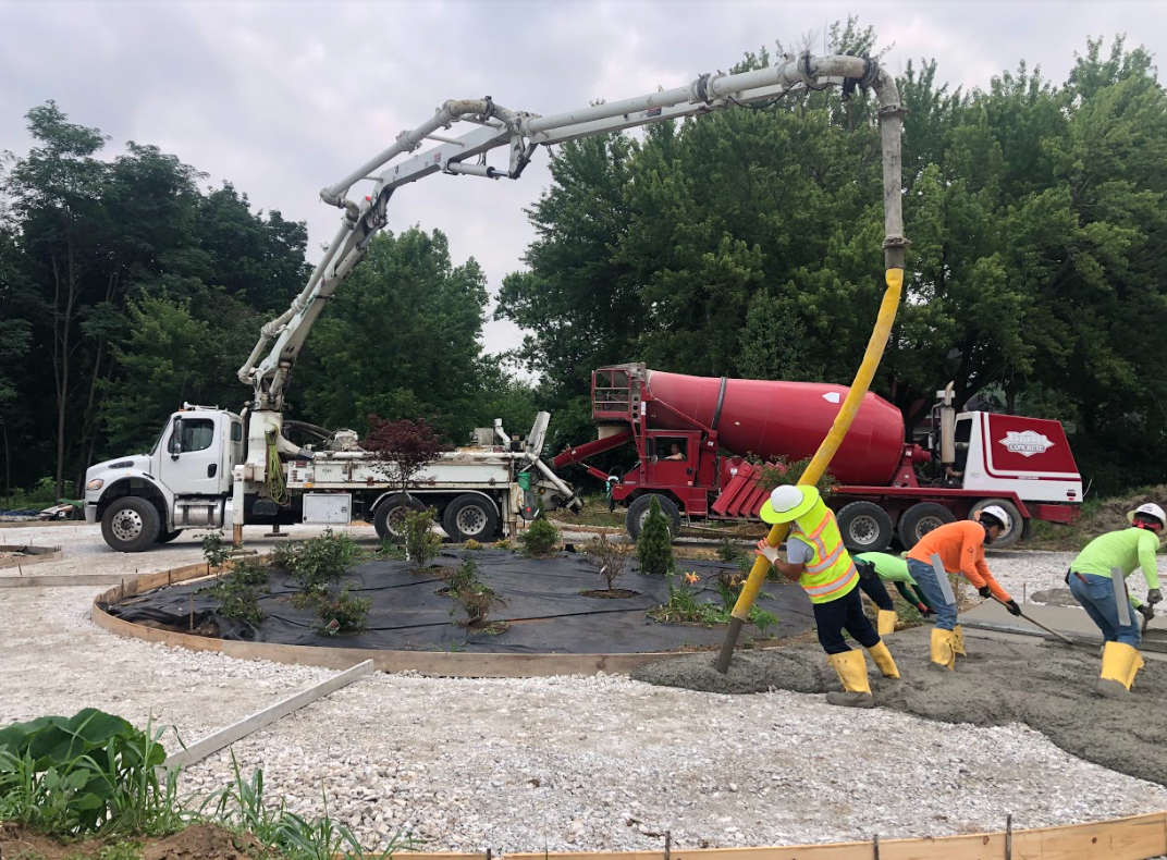 Tipp-Mont Concrete Pumping workers pouring concrete under a flower bed from a large machine in West Lafayette, IN