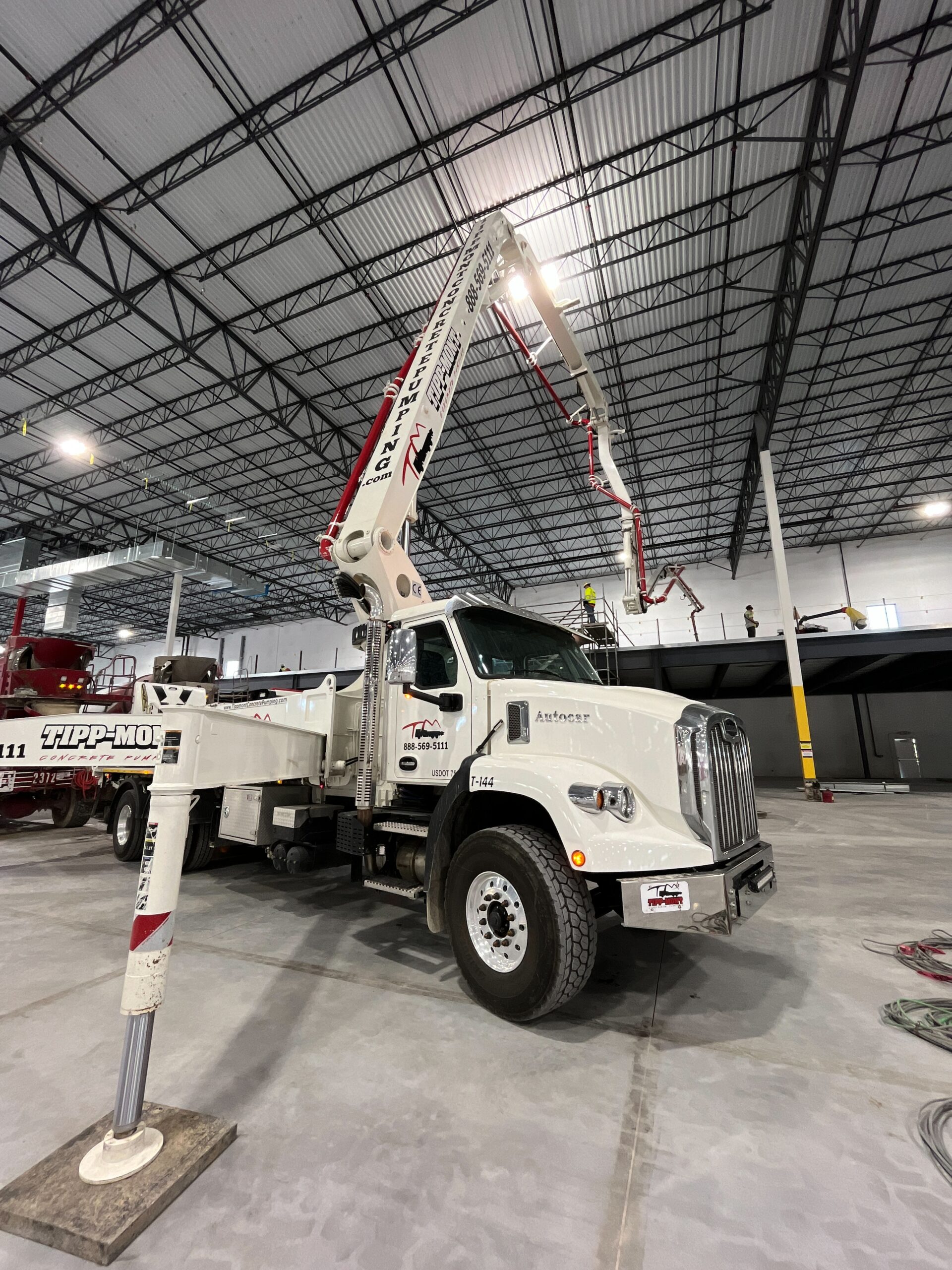 A white and red machine pumping concrete into a warehouse in West Lafayette, IN