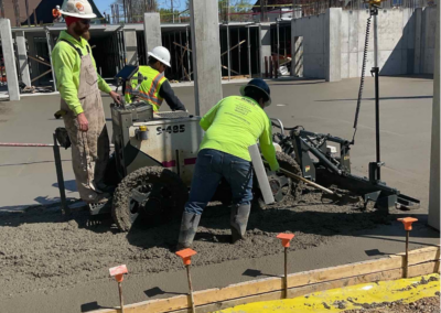 Construction workers collaborating on the installation of a concrete slab, showcasing teamwork and skill on-site, using Laser Screed.