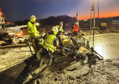 Using Laser Screed, a group of construction workers diligently pouring and smoothing a concrete slab at a construction site.