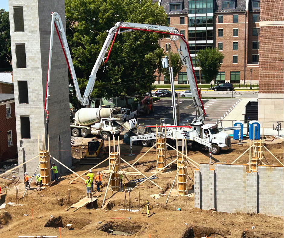 Tipp-Mont Concrete Pumping workers pouring concrete under a flower bed from a large machine in West Lafayette, IN